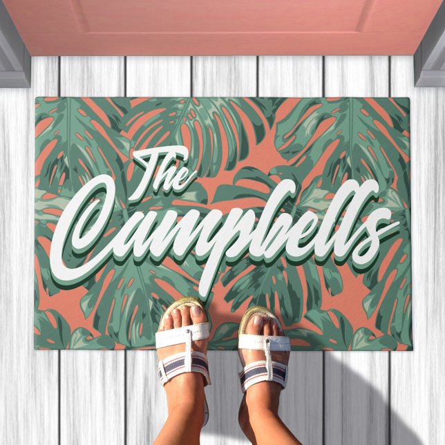 Felpudo Hojas tropicales Script Green Family Name Doormat (Doormat with green leaves on orange background. Text overlay says your family name)