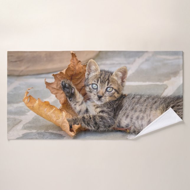 Gatito de Tabby lindo jugando con una hoja - (Toalla de baño)