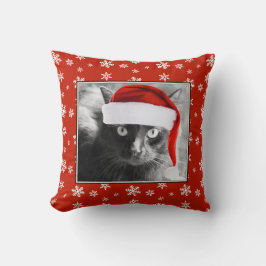 Gato del navidad en la almohada roja con los copos