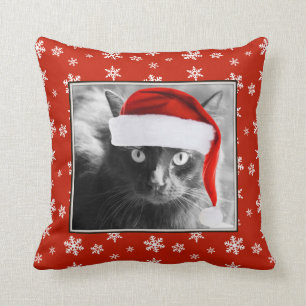 Gato del navidad en la almohada roja con los copos