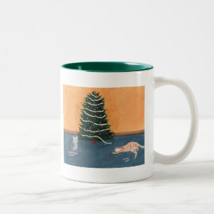Gatos juguetones del navidad por la taza del árbol