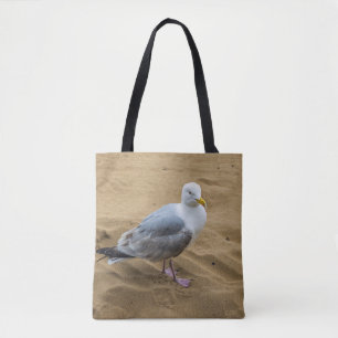 Gaviota en una bolsa de asas de la playa arenosa