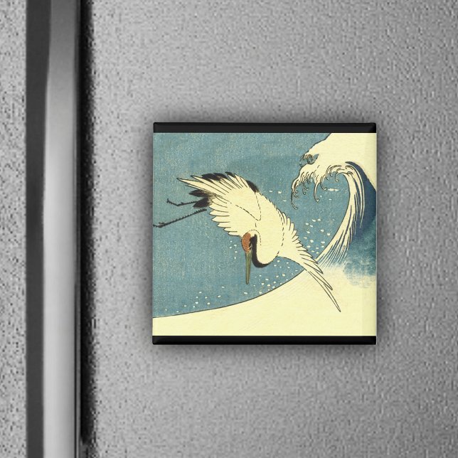 Grúa volando en un imán ondulado (White crane bird flying over blue ocean wave black borders on magnet.)