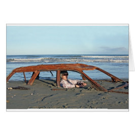 Hombre sentado en un auto oxidado en la playa