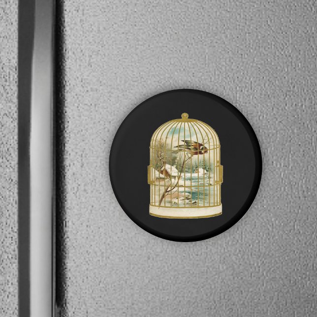 Imán Bird In Cage Winter Scene (Golden birdcage with winter cabin scene inside bird on branch on black round magnet.)