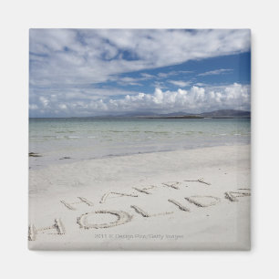 Imán Día de fiesta feliz escrito en la playa de