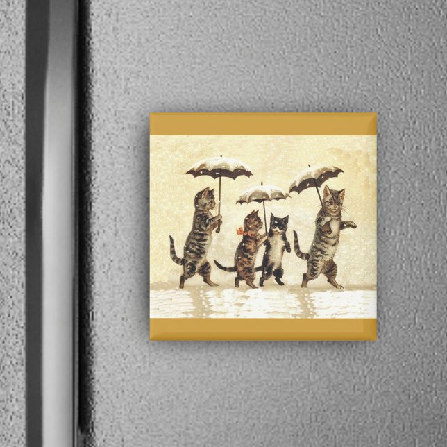 Imán Familia de gatos con paraguas caminando en la niev (Four brown cats walking upright in snow with umbrellas on yellow square magnet.)