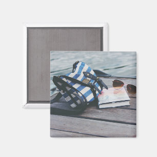 Imán Gafas de sol, libro, bolso en el muelle a orillas 