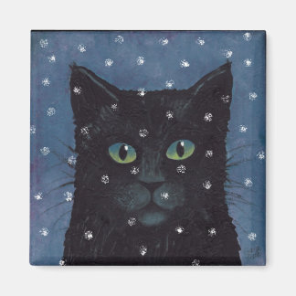 Imán gato negro en nieve de invierno