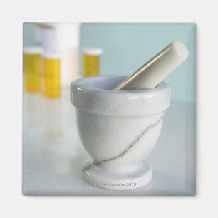 Imán Mortero y maja, botellas de píldora en fondo