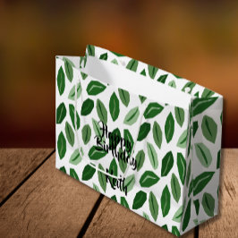 Las hojas verdes en la bolsa de regalo blanca pers