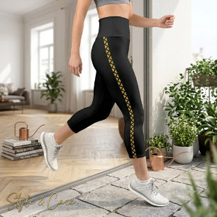 Leggings Capri negros con franja lateral dorada at