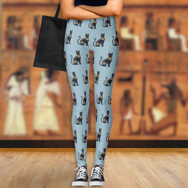 Leggings Gato negro egipcio con estampado azul turbio (A pair of light blue leggings with a pattern of Egyptian-style black and faux gold cats)