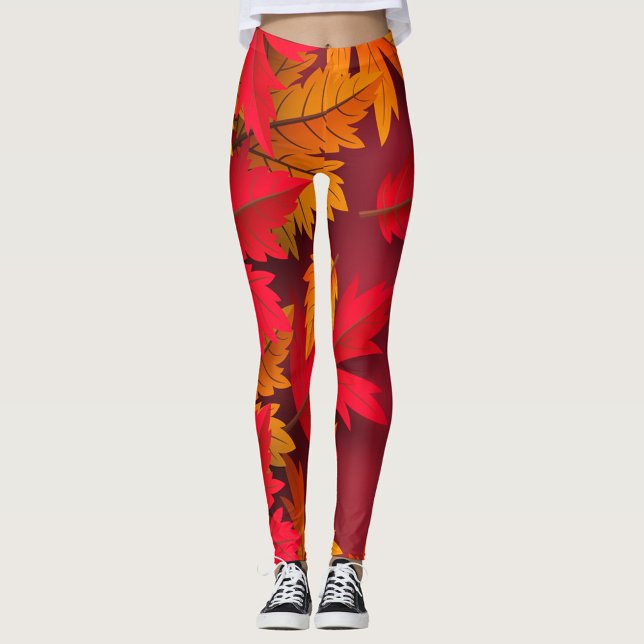 Leggings Otoño ( A model showcases vibrant leggings adorned with autumn leaves in shades of red and orange. )