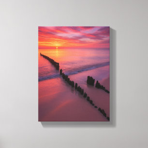Lienzo Atardecer sobre la playa con posts de madera