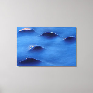 Lienzo Atardecer sobre rocas que atraviesan un agua espum