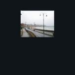 Lienzo Foggy Morning at Scarborough<br><div class="desc">An atmospheric and moody scene of South Bay Beach in Scarborough, North Yorkshire, enveloped in a dense morning fog. Gentle waves lap at the sandy shore in the foreground, creating a foamy edge. The mist partially obscures the vibrant lights of the town and harbor, giving Scarborough a mysterious and ethereal...</div>