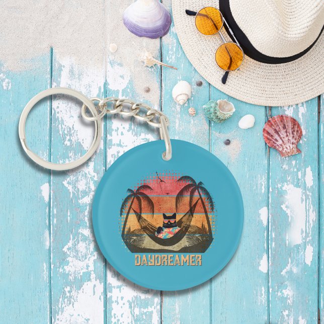 Llavero El sueño de un gato de Guay escapa tropical (A Daydreaming Cool Cat's Tropical Escape Round Keychain on the table.)