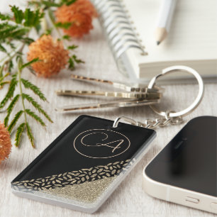 Llavero Las plumas de oro en el monograma negro Purpurinos