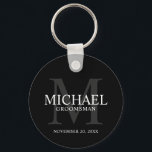 Llavero Nombre y monograma de los groomsmen personalizados<br><div class="desc">Añada un toque personal a su boda con la cadena de teclas personalizada para los groomsmen. Esta cadena de teclas presenta el nombre personalizado del groomsman con título y fecha boda en blanco y monograma en gris como fondo, en estilo clásico de tipo de letra serif, sobre fondo negro. También...</div>