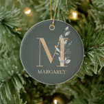 M Monograma Ornamento Cerámico Personalizado Flora<br><div class="desc">Letra M monograma floral. Letra M en textura marrón dorada acentuada con hojas de compuestos de acuarela verde,  flores y polvo de oro. Se personaliza con el nombre en la fuente coincidente.</div>