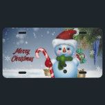 Matrícula Merry Christmas Snowman License Plate<br><div class="desc">En esta placa de licencia de vacaciones aparece una imagen de un muñeco de nieve sosteniendo un bastón de dulces y usando un gorra de Santa. Con el mensaje,  "Feliz Navidad",  ¡úsense o donen como regalo de vacaciones también!</div>