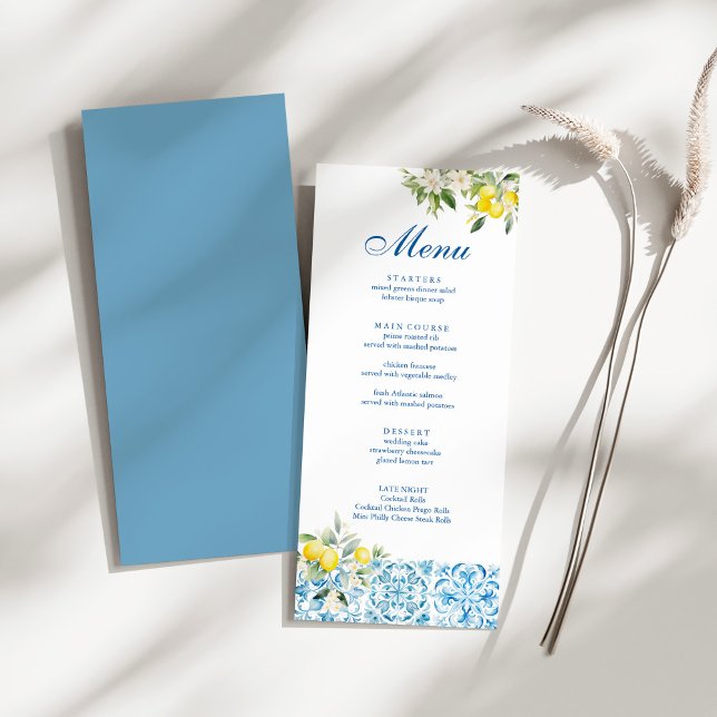 Menú Boda de azulejos y limón azul mediterráneo (Mediterranean Blue Tiles & Lemon Wedding Menu on a sunny white table.)