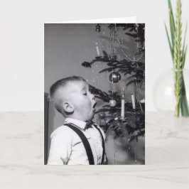 Niño sopla velas en el árbol de Navidad