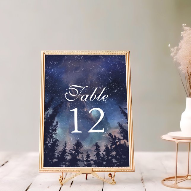 Número de Mesa de Boda Celestial Bosque Nocturno E (Starry Night Forest Wedding Table Numbers on a white wooden table in a golden frame.)