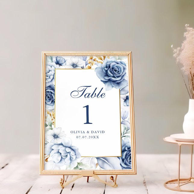 Número de tabla de Boda floral azul y dorado moder (Modern Blue and Gold Floral Wedding Table Number on a rustic white wooden table next to flowers)