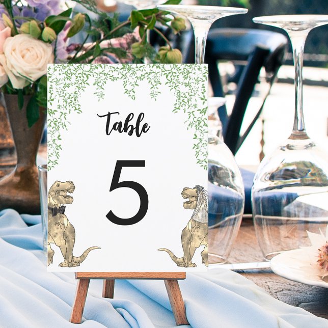 Número de tabla del Boda del tema de los dinosauri (Dinosaur themed wedding table numbers with T-Rex bride and groom and jungle foliage)