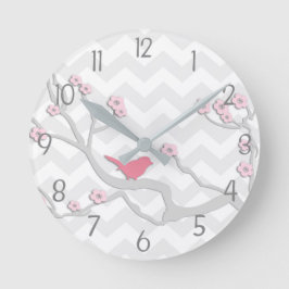 Pájaro gris rosado en el reloj de pared de rama