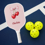 Palas De Pickleball Nombre rosa del arco del cerezo<br><div class="desc">Cerezas rojas con arco rosado. Fondo rosa suave. Personaliza y agrega tu nombre.</div>