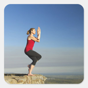 Pegatina Cuadrada la mujer joven practica yoga en un pen¢asco en