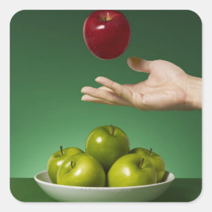 Pegatina Cuadrada mano tirando manzana roja al aire y verde