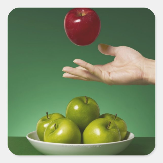 Pegatina Cuadrada mano tirando manzana roja al aire y verde (Anverso)