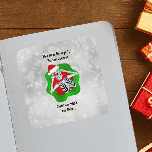 Pegatina Cuadrada Navidades Ornamentos de esqueleto Verde Rojo brill (Cute Skeleton holding ornaments for eyes Santa Hat in green Red splatter on white book plate sticker)
