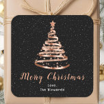 Pegatina Cuadrada Rosa Gold y Black Ribbon Tree Merry Christmas<br><div class="desc">Este elegante y moda pegatina de vacaciones puede ser personalizado con su nombre familiar. El diseño presenta un árbol de Navidad de cinta dorada subió con una estrella. El texto combina el guión manuscrito y las fuentes sans serif modernas para un aspecto elegante y sofisticado. La caída de la nieve,...</div>
