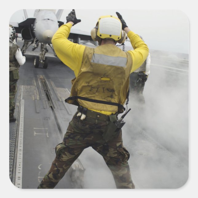 Pegatina Cuadrada Un director de aeronaves señala un avispón F/A-18C (Anverso)