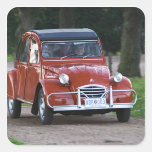 Pegatina Cuadrada Un viejo Citroen 2CV rojo con una mujer sonriente