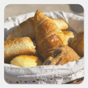 Pegatina Cuadrada Una cesta de mimbre para desayuno con croissants,