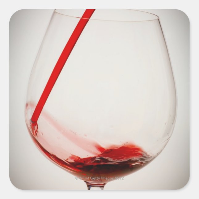 Pegatina Cuadrada Vino rojo vertiéndose en vidrio, de cerca (Anverso)