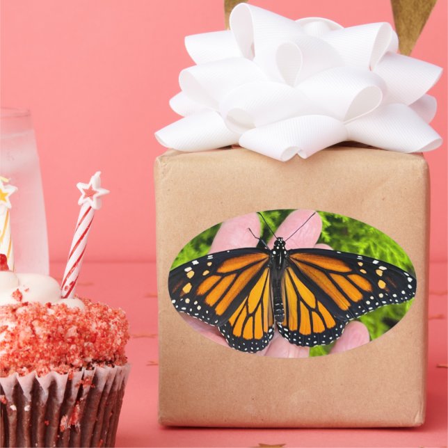 Pegatina Ovalada Portando una mariposa monarca (Fiesta)