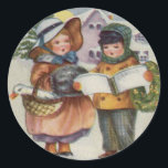 PEGATINA REDONDA CHRISTMAS STICKER - CANTO DE CAROL PARA NIÑOS<br><div class="desc">El diseño es de una tarjeta victoriana y representa a niños con mejillas rojas que desafían los elementos para honrar la tradición de Carol cantando en la nieve.</div>