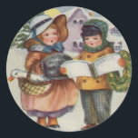 PEGATINA REDONDA CHRISTMAS STICKER - CANTO DE CAROL PARA NIÑOS<br><div class="desc">El diseño es de una tarjeta victoriana y representa a niños con mejillas rojas que desafían los elementos para honrar la tradición de Carol cantando en la nieve.</div>