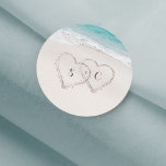 Pegatina Redonda Corazones en la boda de la playa de destino de are<br><div class="desc">Cuenta con dos corazones en la arena y las iniciales de la novia y del novio,  con agua turquesa y fondo de playa de arena blanca,  ideal para bodas de playa de verano o bodas de destino tropical.</div>