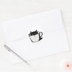 Pegatina Redonda Gatito negro con nariz roja escondido en una taza