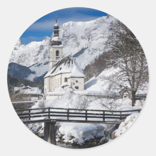Pegatina Redonda Iglesia en la nieve con los Alpes