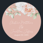 Pegatina Redonda Melocotones románticos y flores blancas<br><div class="desc">Este romántico pegatina boda floral presenta un elegante fondo de melocotón polvoriento con melocotón acuático y flores blancas. En la parte superior hay un ramo delicado. Los nombres de ejemplo de una pareja se imprimen debajo en un elegante tipo de letra.</div>