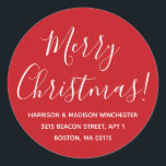 Pegatina Redonda Merry Christmas red white script return address<br><div class="desc">Feliz Navidad personalizado blanco y rojo moderno caligrafía nombre y dirección Navidades personalizados regresan pegatinas de direcciones. Texto blanco completamente personalizable,  fondo rojo. Diseño elegante,  sencillo y moderno.</div>